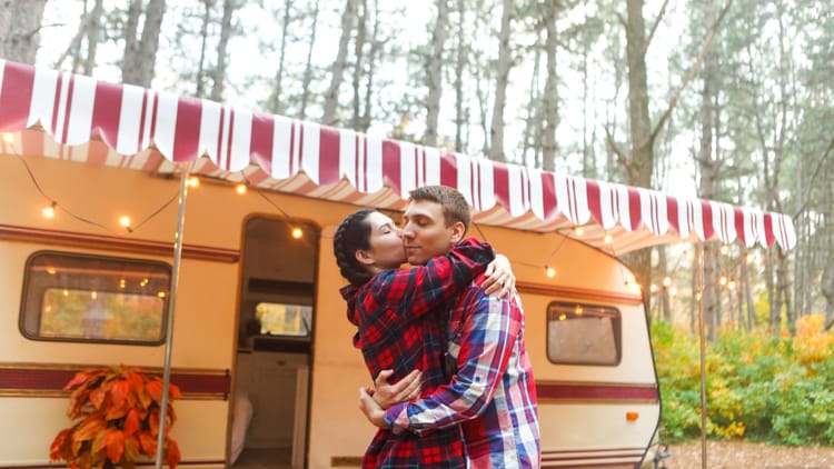 a couple hugging outside their travel trailer after downsizing for RV life